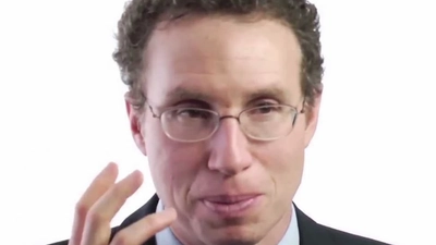 Man in glasses speaking to camera.