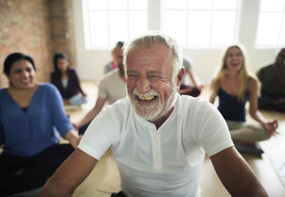 Laughing mature man enjoying yoga class.